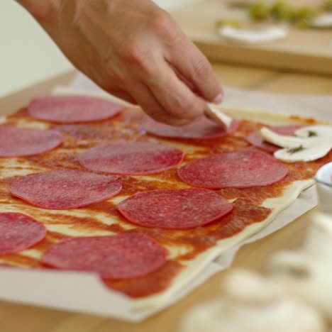 woman making a homemade salami and mushroom pizza