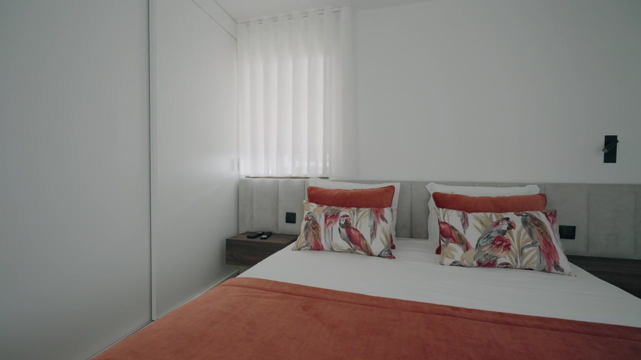 Camera da letto bianca e pulita con copriletto arancione chiaro e morbido e cuscini decorativi