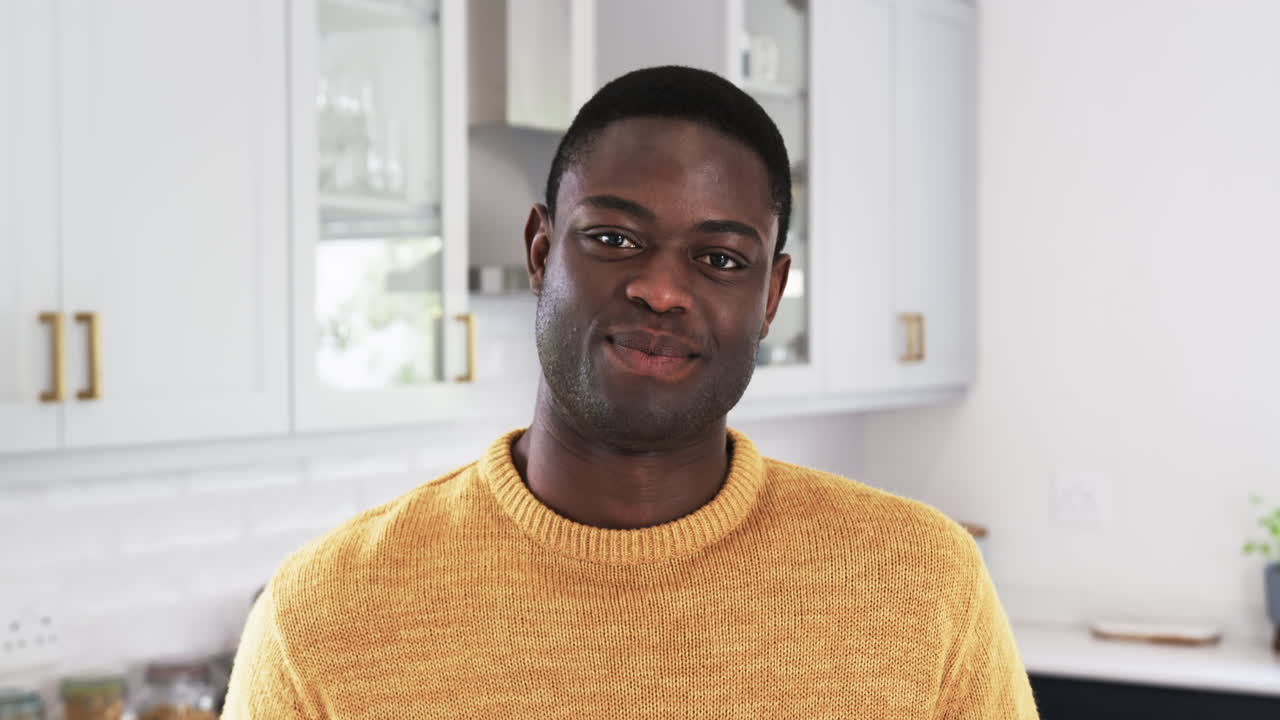 Uomo afroamericano con un maglione accogliente che sorride calorosamente a casa durante il periodo natalizio.