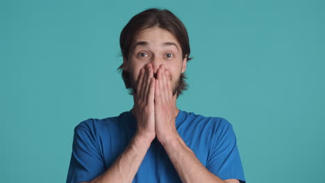hombre feliz caucásico frente a la cámara sobre un fondo azul.