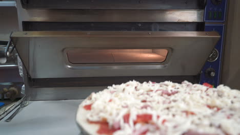 chef puts a raw pizza into the oven. making pizza. cooking food.