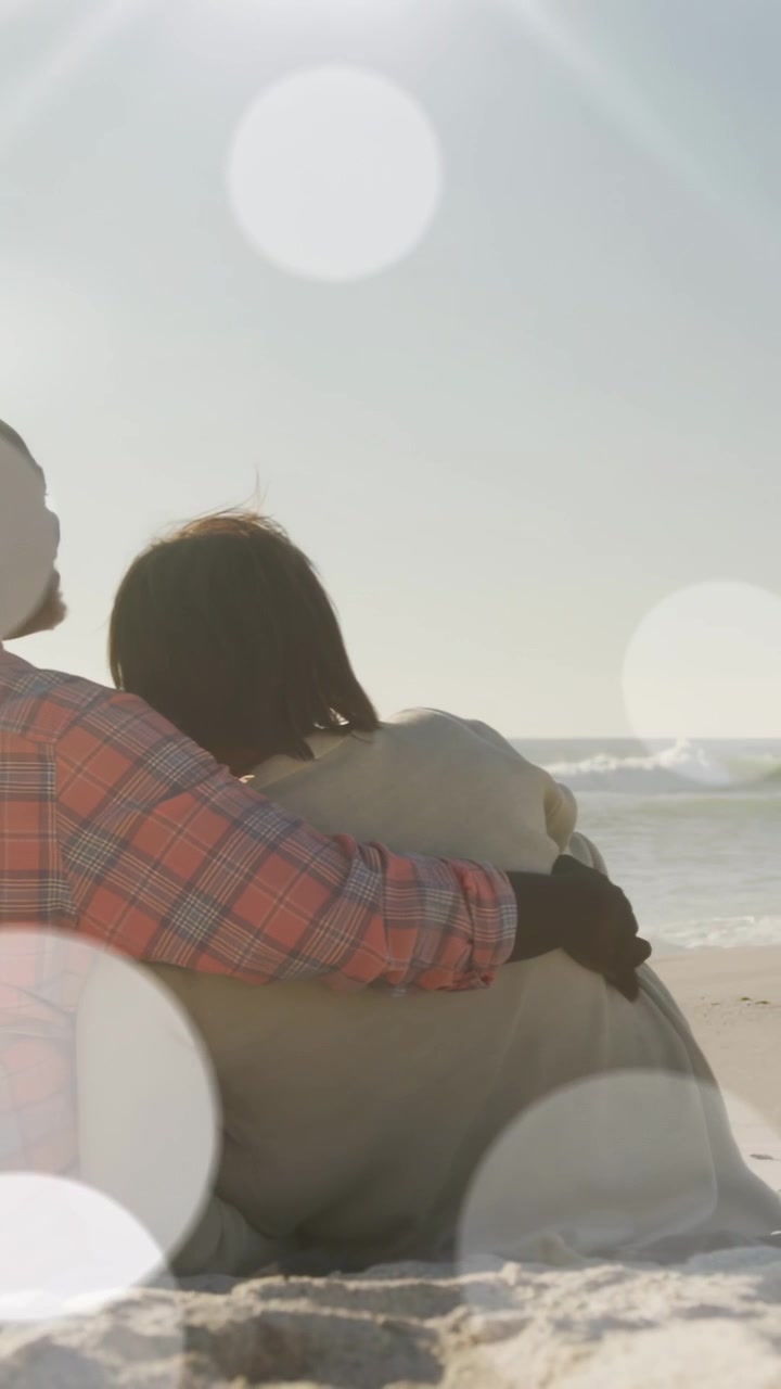 Video verticale: Uomo che le cinge le spalle, lei si appoggia per un bokeh panoramico e calmo sulla coppia o con l'oceano sullo sfondo.