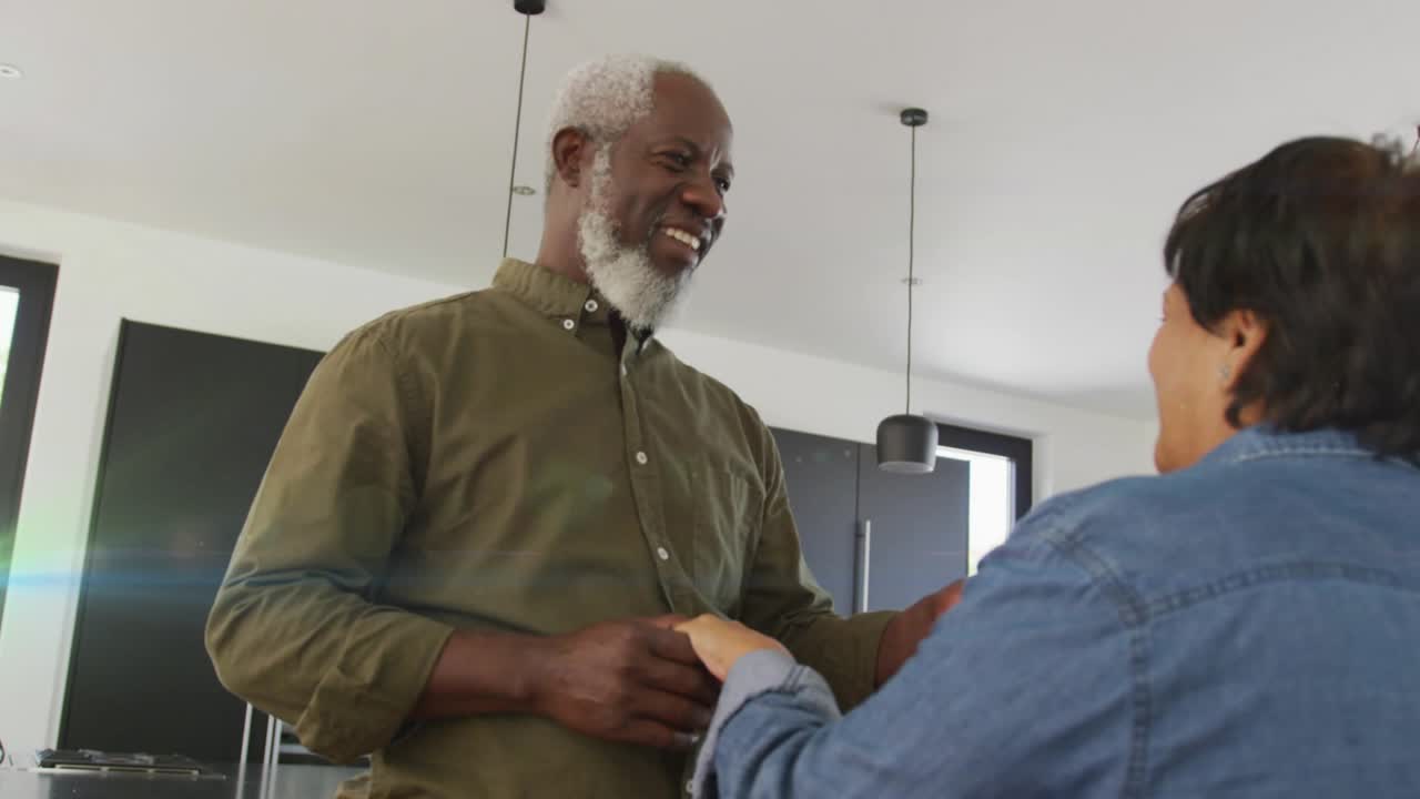 Bearded man and woman holding hands in kitchen, man placing ring amid green tech flare passing