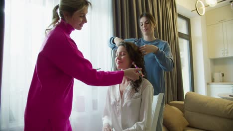 beautiful bridesmaids are getting bride ready for wedding at home