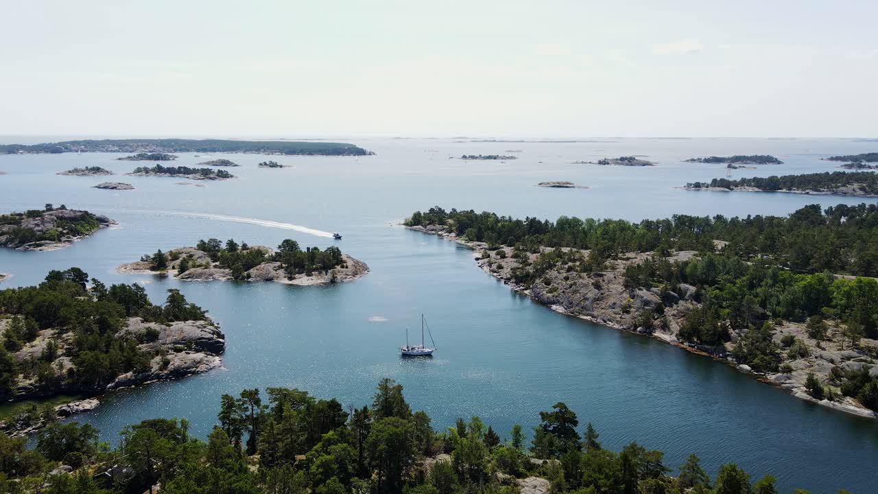 Swedish archipelago - anchored yacht with speedboat cruising past small islands