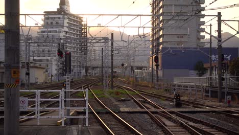 Paisaje-Urbano-En-Las-Vías-Del-Tren-Con-Puesta-De-Sol-En-El-Fondo