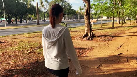 young fit latina woman in hoodie exercises in urban area next to busy street with traffic