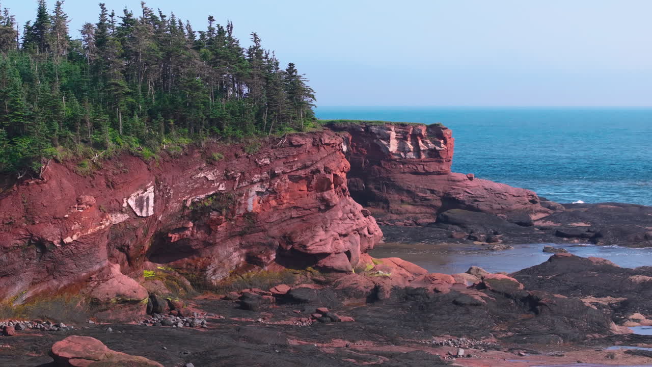 aerial touring around the red cliffs of Duckpond Beach in the Maritimes of Canada
