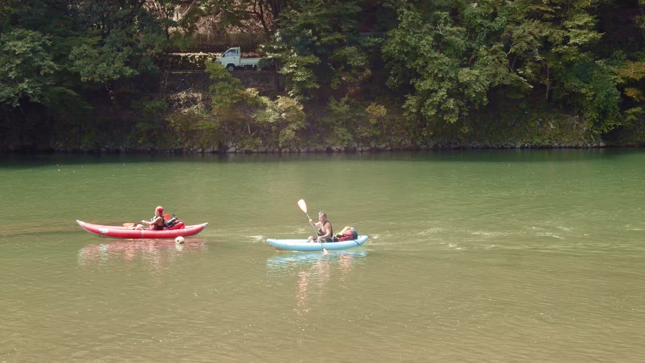 Slide shot of people kayaking down a river in Kyoto, Japan 4K slow motion