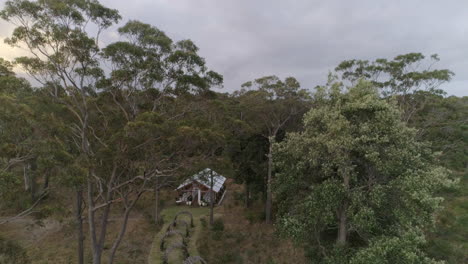 Event-venue-in-the-forest-with-white-chars-and-arched-pathway,-drone-push-in