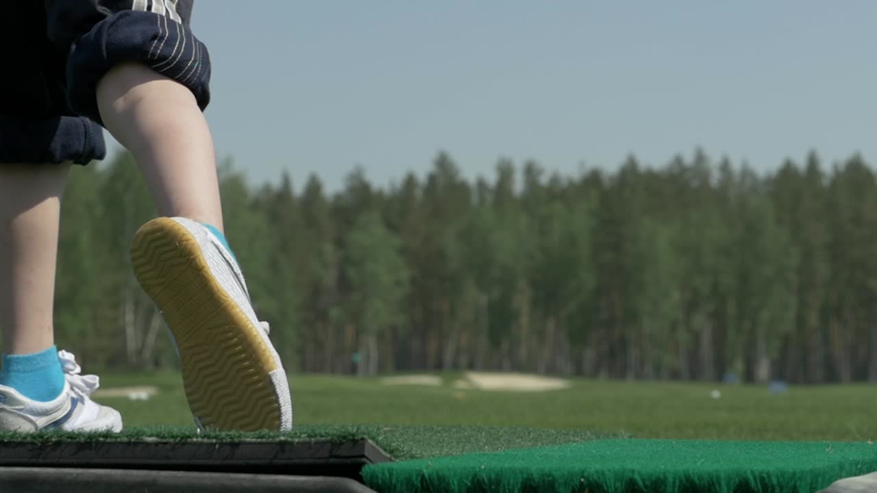 어린이 가 드라이빙 레인지 에서 골프 를 연습 하고 있다