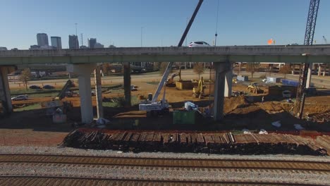 cars drive over busy city overpass and equipment during on ramp construction project