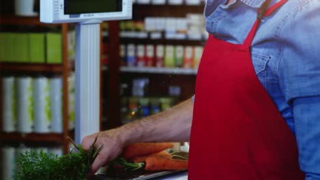 personal sonriente sosteniendo un ramo de zanahorias en la sección orgánica