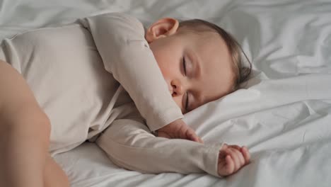 un video de una niña caucásica durmiendo en la cama de su casa.