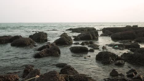 Rocky-shoreline-with-gentle-waves-during-an-overcast-evening