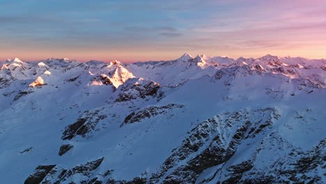 Drone-footage-capturing-the-serene-beauty-of-the-South-Tyrolean-Alps-in-winter,-with-the-camera-tilting-up-to-reveal-the-snow-clad-mountains-at-sunrise