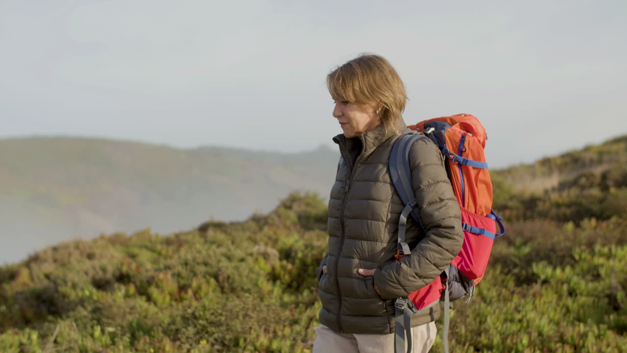 toma de seguimiento de una anciana con mochila caminando por las montañas y mirando alrededor