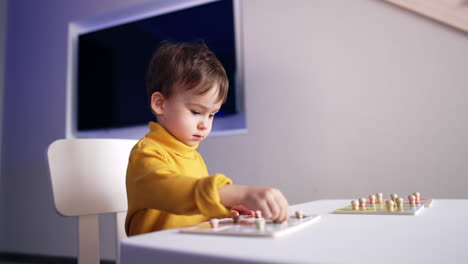attentive cute baby boy playing with his puzzles at desk. lovely toddler studying through the game.