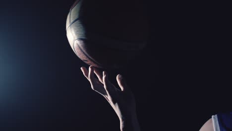 a female basketball player spinning a basketball in super slow motion in a backlit scene creating a silhouette like figure