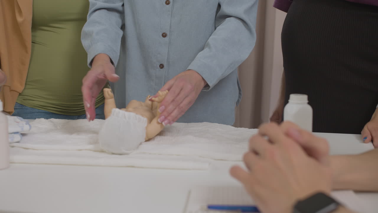 두 명의 임산부와 장난감 아기를 데리고 수업 중인 교사