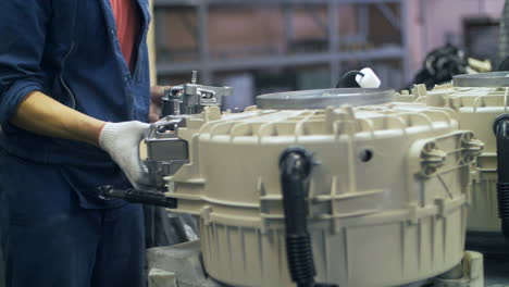 industrial worker collecting drums for domestic washing machine at factory