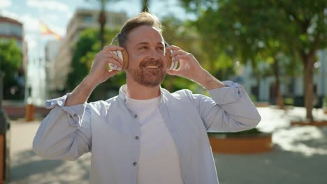 young caucasian man smiling confident listening to music at park