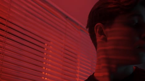 close-up portrait of a person in a dimly lit room with red light