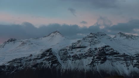 clouds over snow covered mounain peaks illluminated at dusk, telephoto time lapse