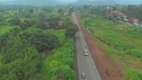 pan tilt up reveal drone shot of rural indian road hills foggy haze