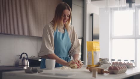 housewife is making dough for pie or domestic bread in home kitchen, kneading pastry by hands on table