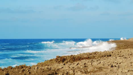 Slow-Motion-waves-crashing-on-rocky-shoreline-in-Curacao-on-sunny-day