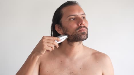 a man is trimming his facial hair with an electric razor to look attractive