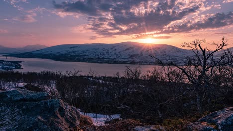 un lapso de tiempo de la puesta de sol visto desde la isla de tromsøya con partículas de arena del desierto del sahara en el aire haciendo un color especial