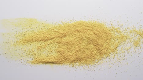 Video-of-close-up-of-yellow-sand-grains-and-copy-space-on-white-background