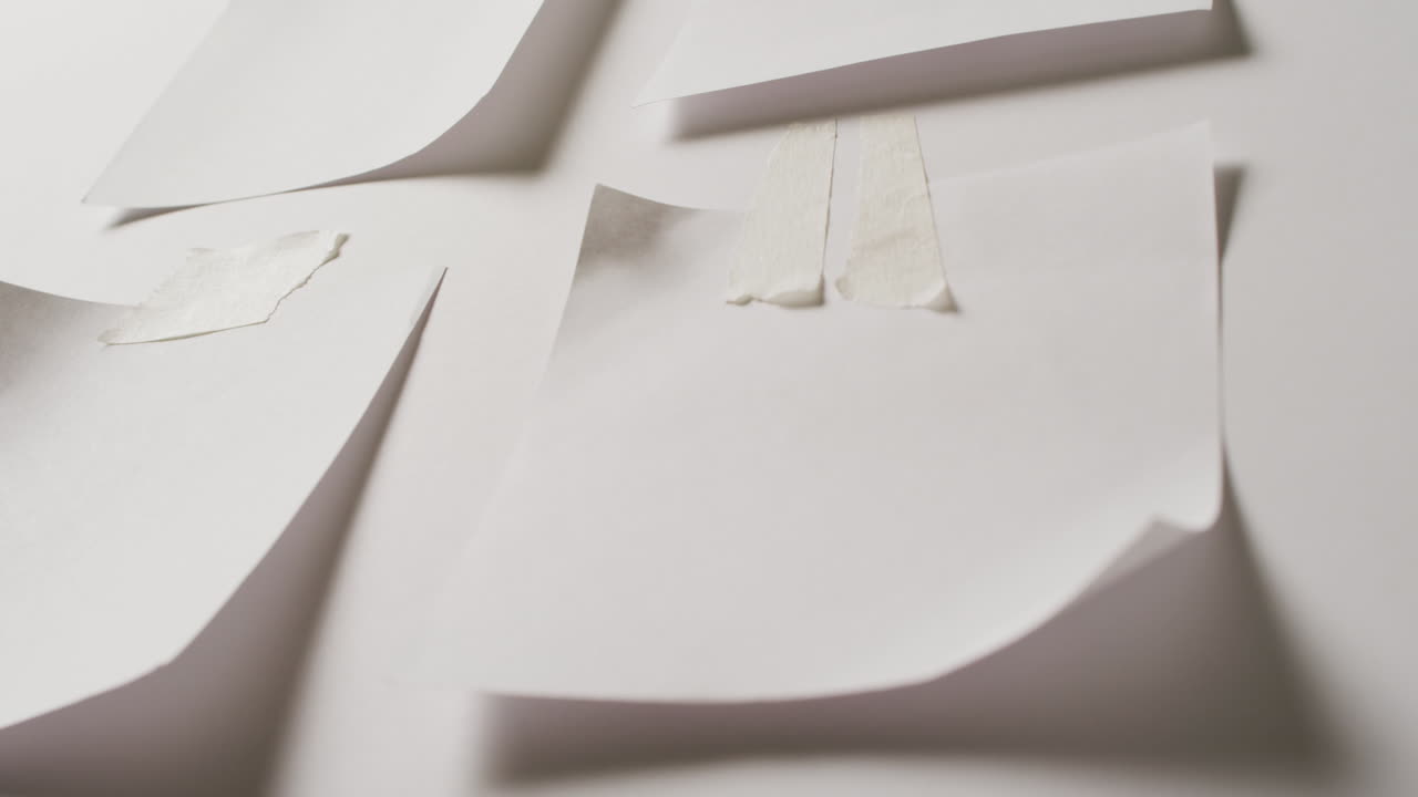 Video of close up of four white memo notes with copy space taped to white background