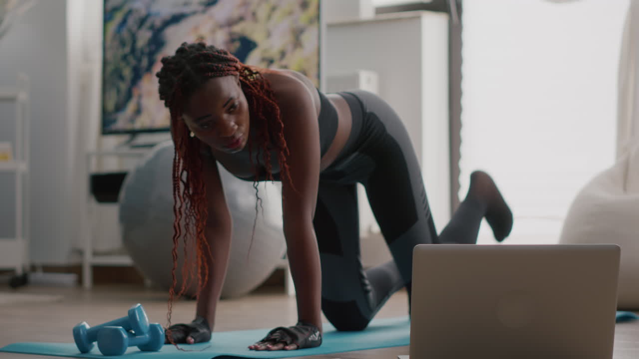 Black sport woman doing morning fitness routine watching fitness video
