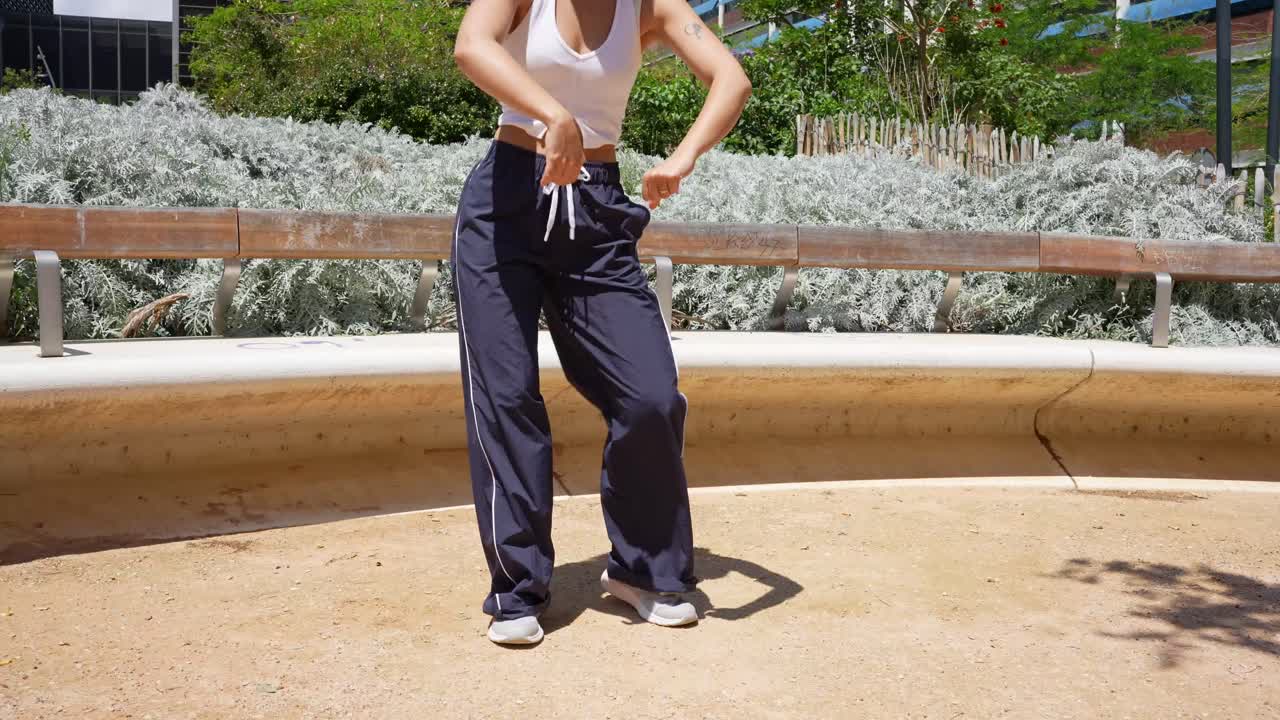 Woman in track pants and white top in an urban park