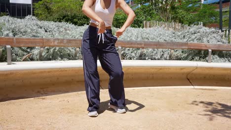 woman in track pants and white top in an urban park