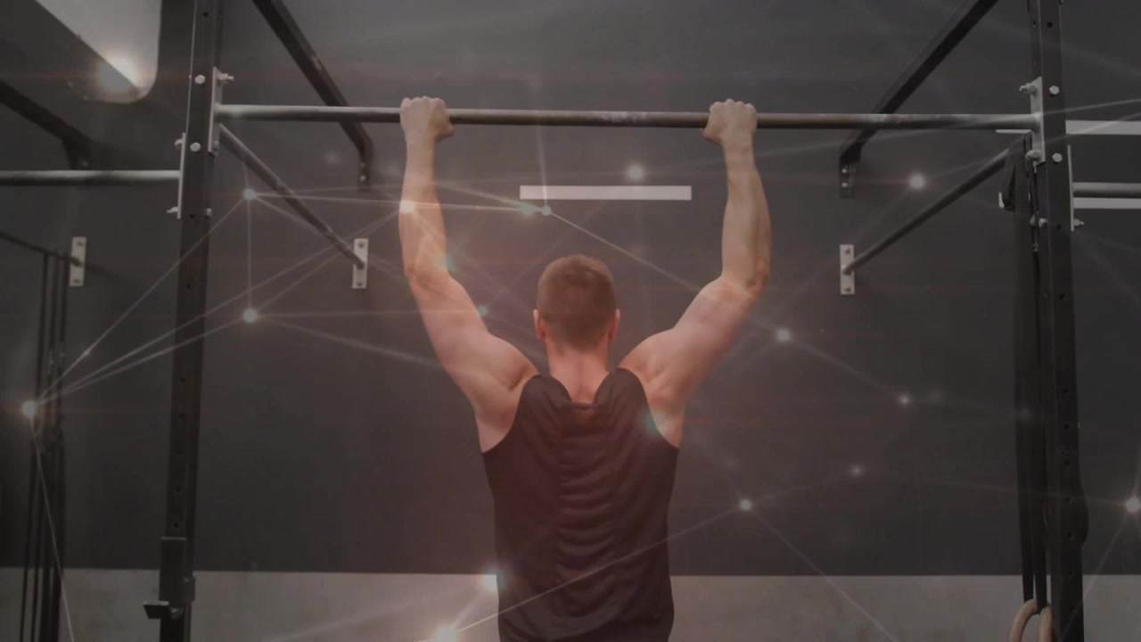 Mand griber pull-up-stang og udfører pull-ups i fitnesscenter, partikelnetværk fremhæver muskelvækst.