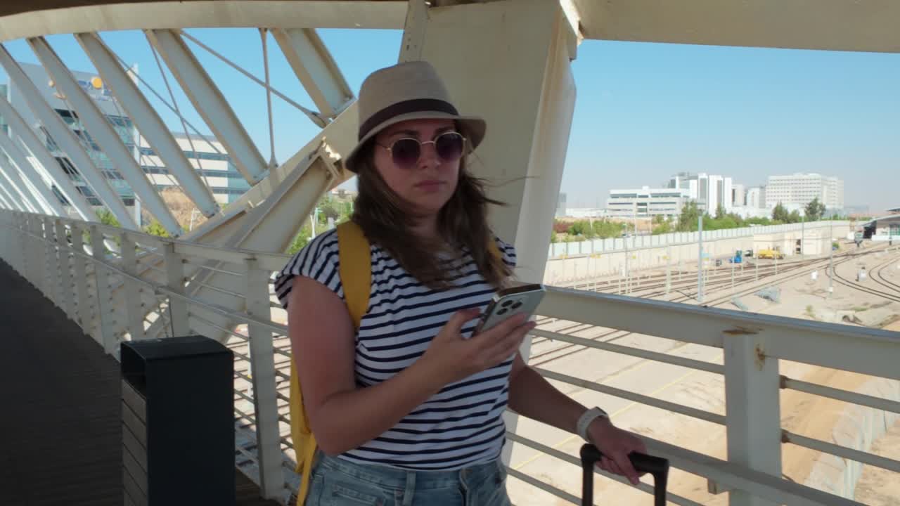 Woman Using Phone on a Bridge Over Train Tracks