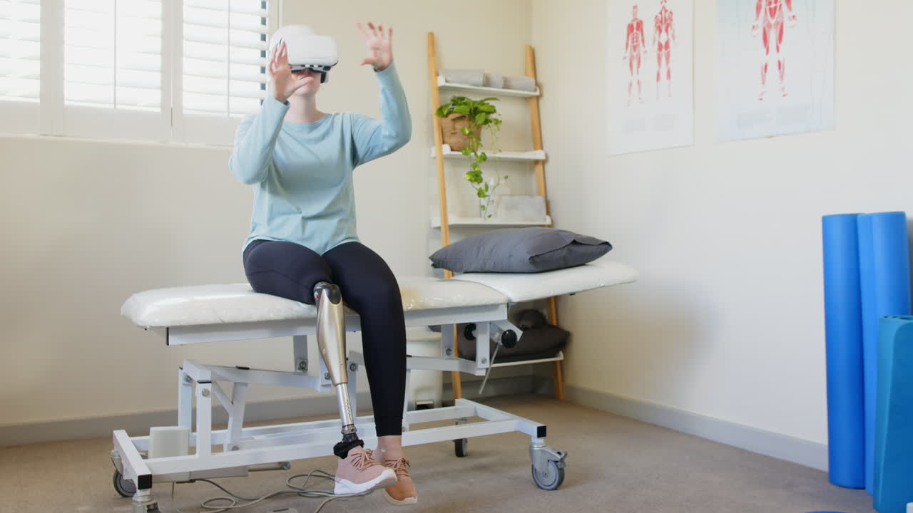 Woman with prosthetic leg sitting on medical table using VR headset