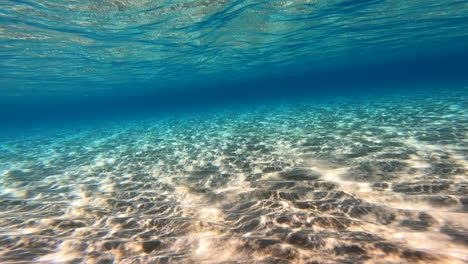 Vista-Submarina-Del-Lecho-Marino-En-Grecia,-Arena-Y-Agua-Azul-Opaca