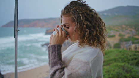 pensive woman sipping cup spending vacation on ocean close up. lady enjoy sea