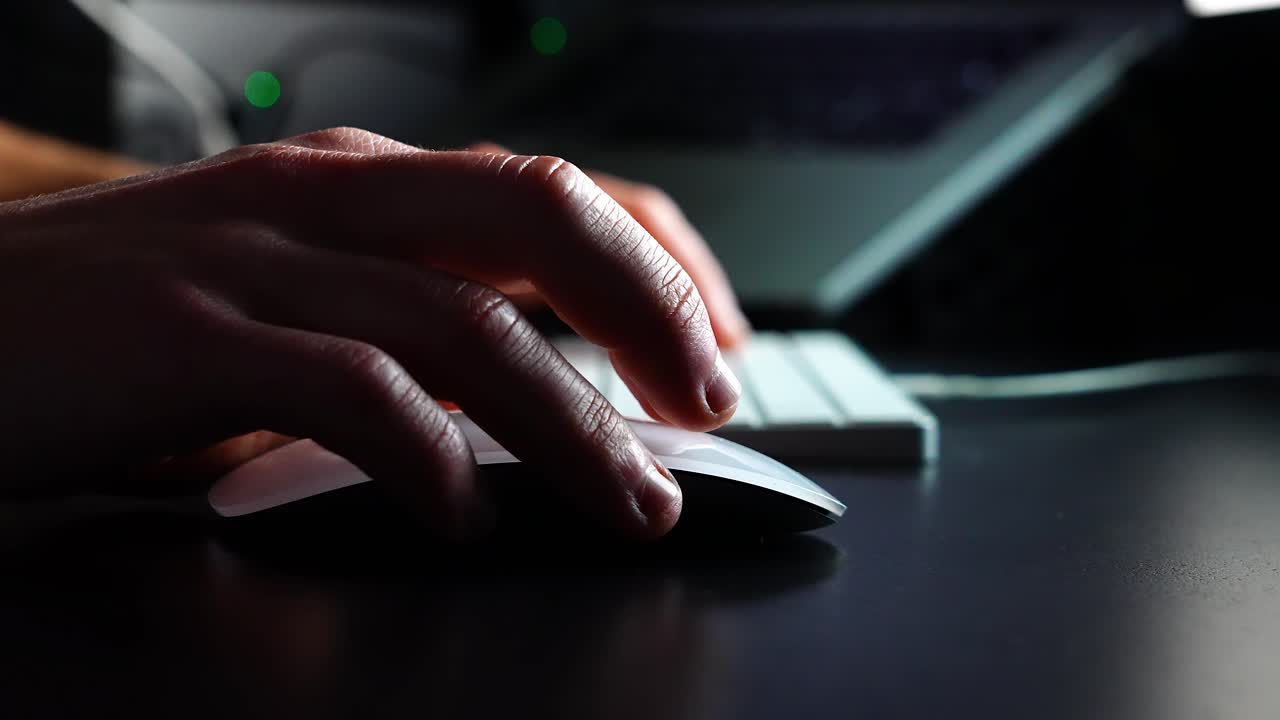 Close-Up of a Creative Professional Using a Mouse and Keyboard in a Dimly Lit Workspace, Engaging in Digital Design