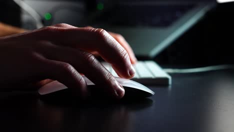 close-up of a creative professional using a mouse and keyboard in a dimly lit workspace, engaging in digital design