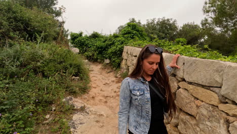 female traveler walking on trekking trail with rock wall