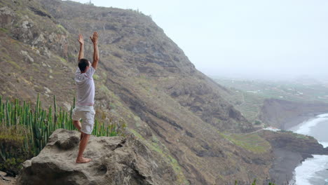 against the picturesque mountain-ocean panorama, a fit young man harmonizes meditation and exercise through sun salutation yoga