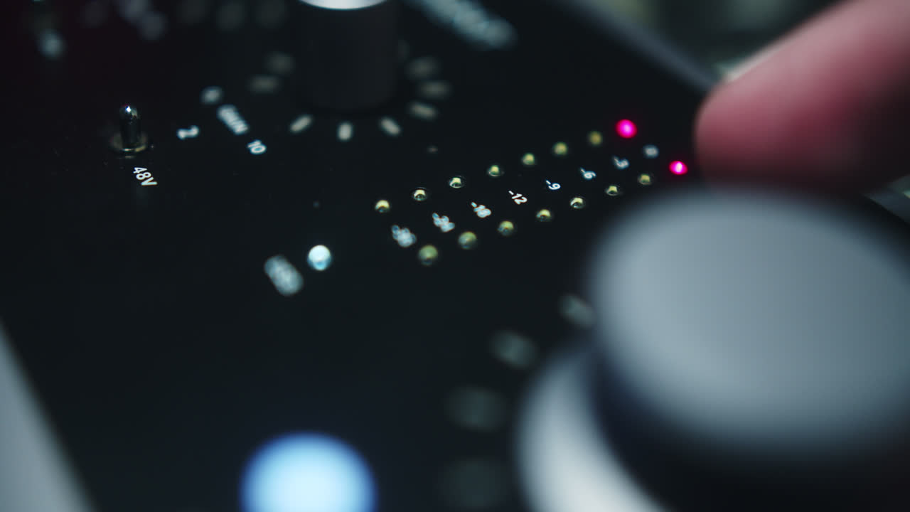 Beautiful slow motion shot of a sound interface being manipulated by a man's hand as he adjusts the volumes and we see the lights on the volumeters moving.
