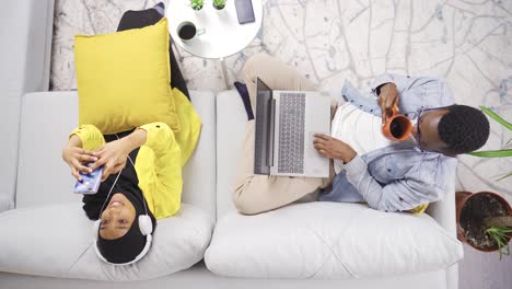 African-muslim-couple-busy-with-technology-devices-at-home-are-happy.