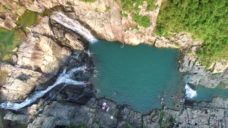 personas que se relajan durante las vacaciones de verano, cascadas de la piscina de roca sai kung y agua azul fresca, hong kong, vista aérea estática de 4k